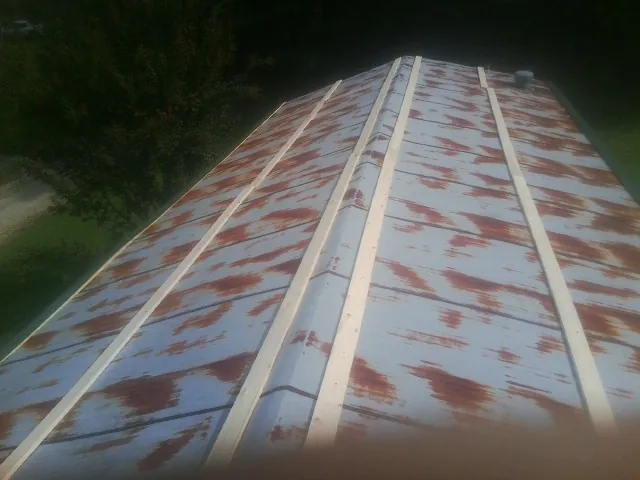 Rusted metal roof panels with new wood purlins before replacement — Storm Damage Roof Repair in Curtis Bay by Roofing Brothers