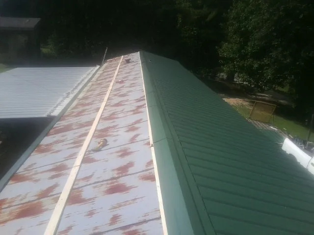 Old rusted panels beside newly installed green metal roofing — Wind Damage Roof Repair by Roofing Brothers in Curtis Bay