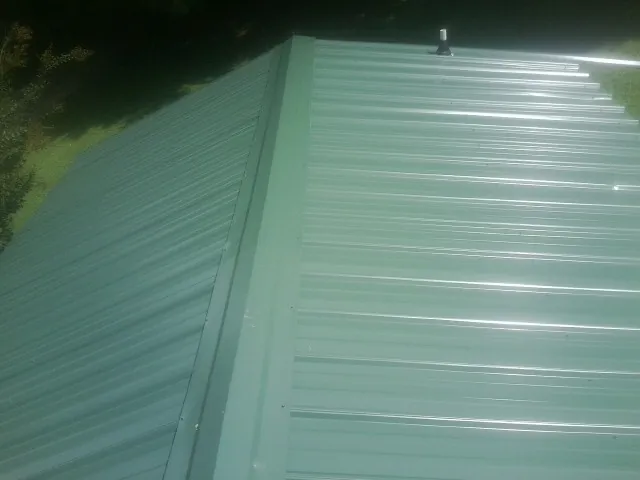 New green metal panels meeting at the ridge of a roof — Flat Roof Repair work by our crew in Curtis Bay