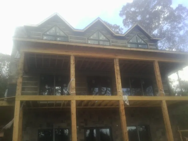 Dormers and porch framing on a large log home under construction — Roof Coating work by our crew in Curtis Bay