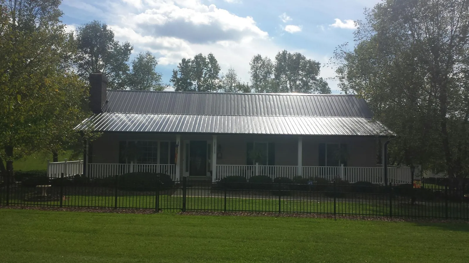 Gray metal roof on a brick ranch with a full width front porch — Gutter Guard Installation work by our crew in Curtis Bay