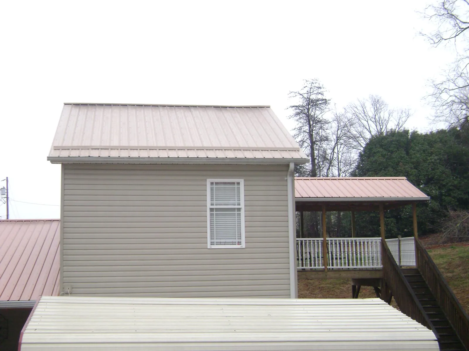 Tan metal roofs on a two story addition and attached porch, from a Roof Replacement job in Curtis Bay