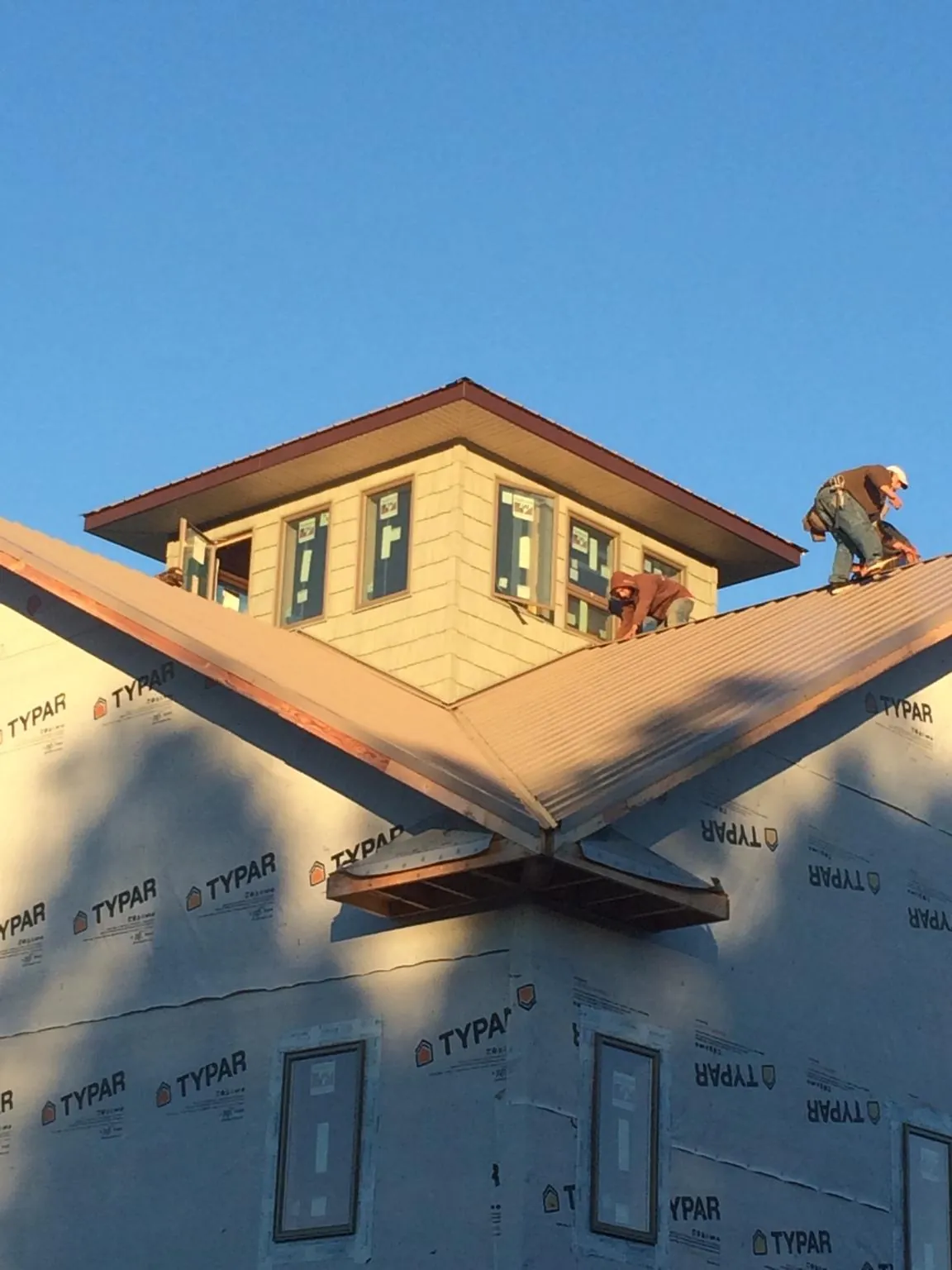 Roofers working around a rooftop cupola on a new metal roof at sunset — Roof Waterproofing in Curtis Bay by Roofing Brothers
